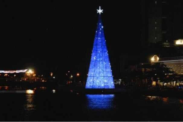 Árvore de Natal com cds e dvds iluminada na cor azul, dentro do rio capibaribe, no Recife.