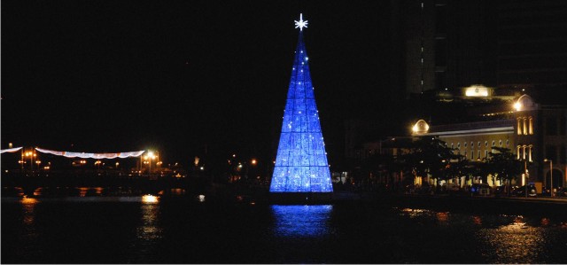 Árvore de Natal com cds e dvds iluminada na cor azul, dentro do rio capibaribe, no Recife.
