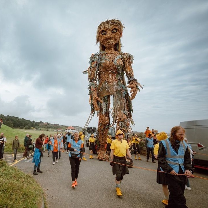 Boneca gigante de materiais recicláveis passeando nas ruas de glasgow